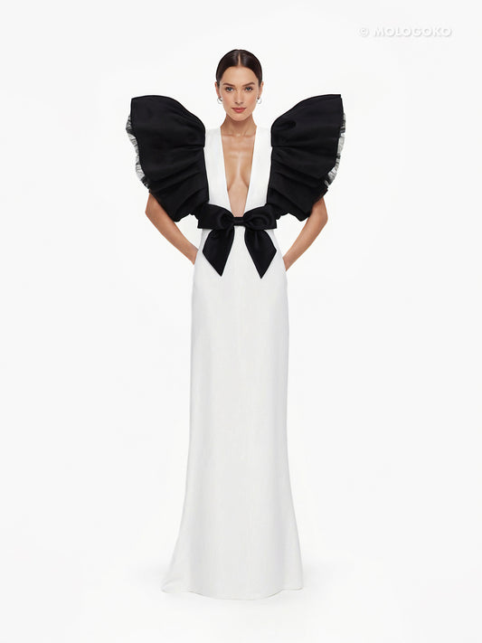 Black and White Monique Gown with dramatic ruffled sleeves, plunging neckline, and black bow detail on white floor-length dress