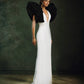 Black and White Monique Gown with dramatic ruffled sleeves and plunging neckline against dark green backdrop